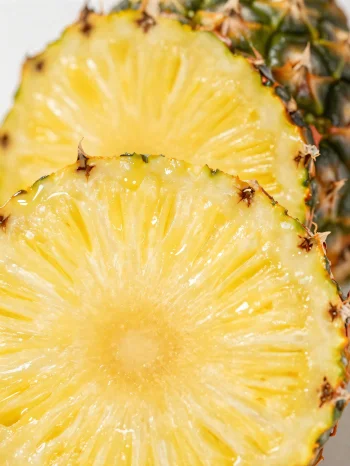 Ananas proaspăt, feliat, pe o masă rustică de lemn