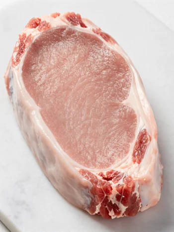 Bucăți proaspete de carne de vițel de culoare deschisă cu condimente pe tocător