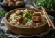Zongzi cu carne înăbușită împachetat în frunze de bambus, servit cu ceapă verde proaspătă